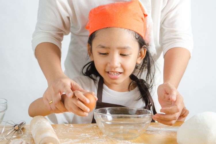 Ilustrasi seorang anak ikut memasak bersama ibunya di dapur.