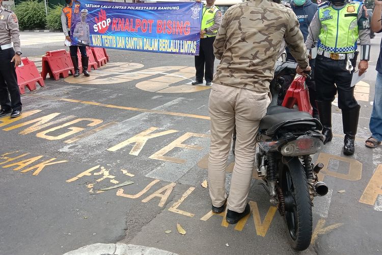 Polisi tampak memberhentikan satu pengendara motor yang menggunakan knalpot bising saat melakukan sosialisasi penggunaan knalpot tak sesuai standar di perempatan Jalan Merdeka, Kota Bandung, Rabu (26/1/2022).