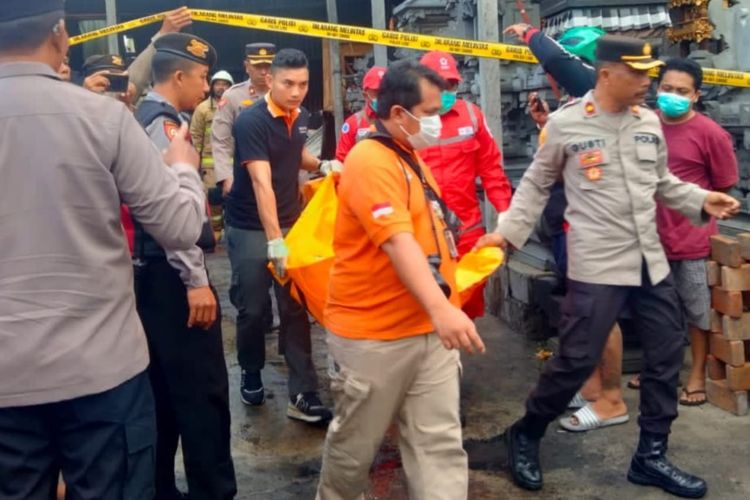 Petugas kepolisian saat mengevakuasi jenazah, KS (9), yang tewas dalam peristiwa kebakaran rumah sekaligus tempat usaha kerajinan sanggah (tempat menaruh sesajen umat Hindu) di Jalan Raya Darmasaba, Desa Darmasaba, Kecamatan Abiansemal, Kabupaten Badung, Bali, Senin (31/7/2023).