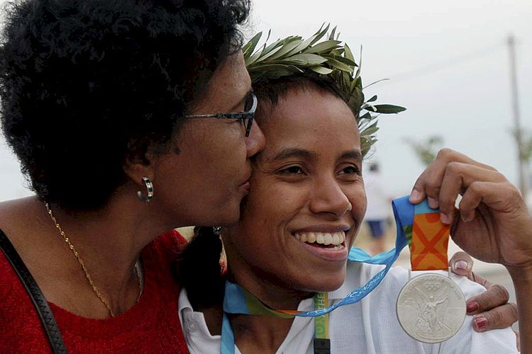 Lisa Rumbewas mendapat ciuman dari ibunya seusai meraih medali perak Olimpiade Athena 2004 nomor angkat besi di kelas 53 kilogram, Senin (15/8/2004). Sebelumnya, Lisa juga mempersembahkan medali perak untuk Indonesia di ajang Olimpiade Sydney 2000 dari nomor angkat besi kelas 48 kilogram. Terkini, Lisa Rumbewas meninggal dunia di RSUD Jayapura, Papua, Minggu (14/1/2024). 
