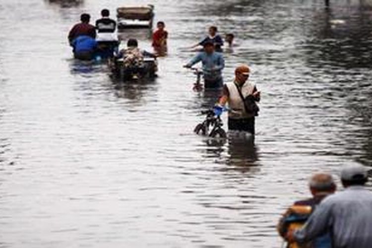 Warga melintasi Jalan Mohammad Toha, penghubung Kota Bandung dengan Dayeuh Kolot, Kabupaten Bandung, yang lumpuh akibat terendam banjir, Rabu (27/3/2013). Selain merendam ribuan rumah warga Bandung Selatan, banjir akibat luapan Sungai Citarum ini melumpuhkan jalan raya yang menjadi salah satu jalur ekonomi dan jalur pengiriman industri pabrik-pabrik di Bandung Selatan. Puluhan truk terhenti serta warga pun hanya bisa mengandalkan alat transportasi non mesin, seperti sepeda, becak, delman dan perahu.

