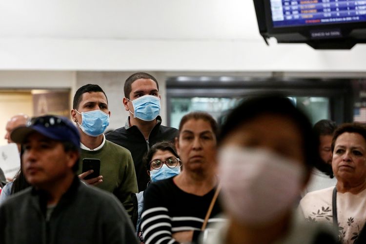 Raphael Hidalgo dan temannya mengenakan masker operasi sebagai langkah pencegahan akan merebaknya virus corona di China, ketika mereka tengah menunggu rekan yang mendarat dari penerbangan di Miami di Bandara Internasional Benito Juarez, Meksiko, pada 24 Januari 2020.