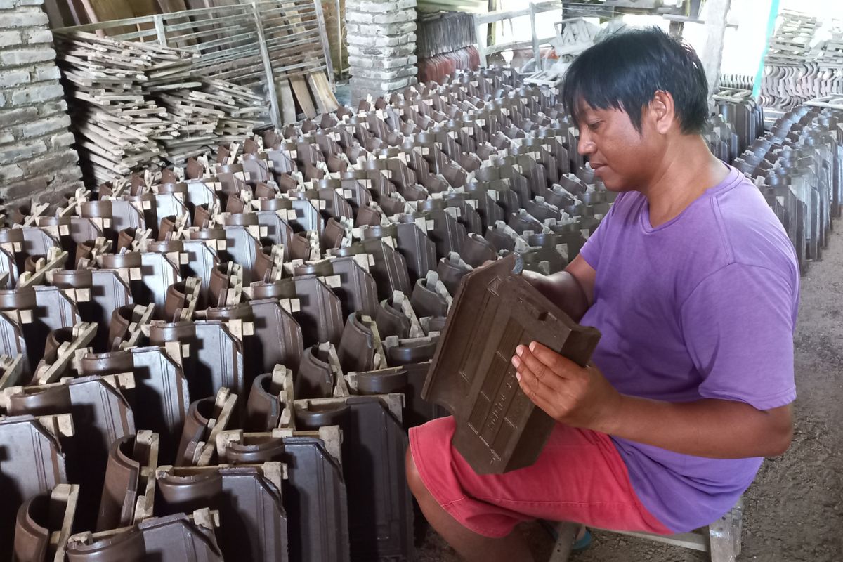 Seorang perajin memeriksa genting di sentra industri genting Desa Manyaran, Kecamatan Banyakan, Kabupaten Kediri, Jawa Timur.