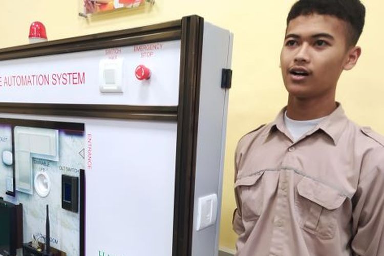 Siswa SMK Negeri 1 Kota CImahi, Jawa Barat, Yoga Ferdi Utama, berdiri di samping panel kelistrikan home automation system bantuan Schneider Electric Indonesia pada program Center of Excellence (CoE), Jumat (24/3/2023).