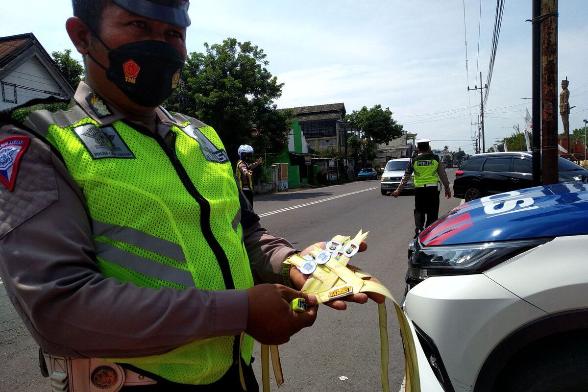 Petugas kepolisian dari Satlantas Polres Blitar memasang pita janur kuning pada kendaraan pemudik yang melakukan pelanggaran di Jalan Kusumabangsa, Kanigoro, Kabupaten Blitar, Minggu (24/4/2022)