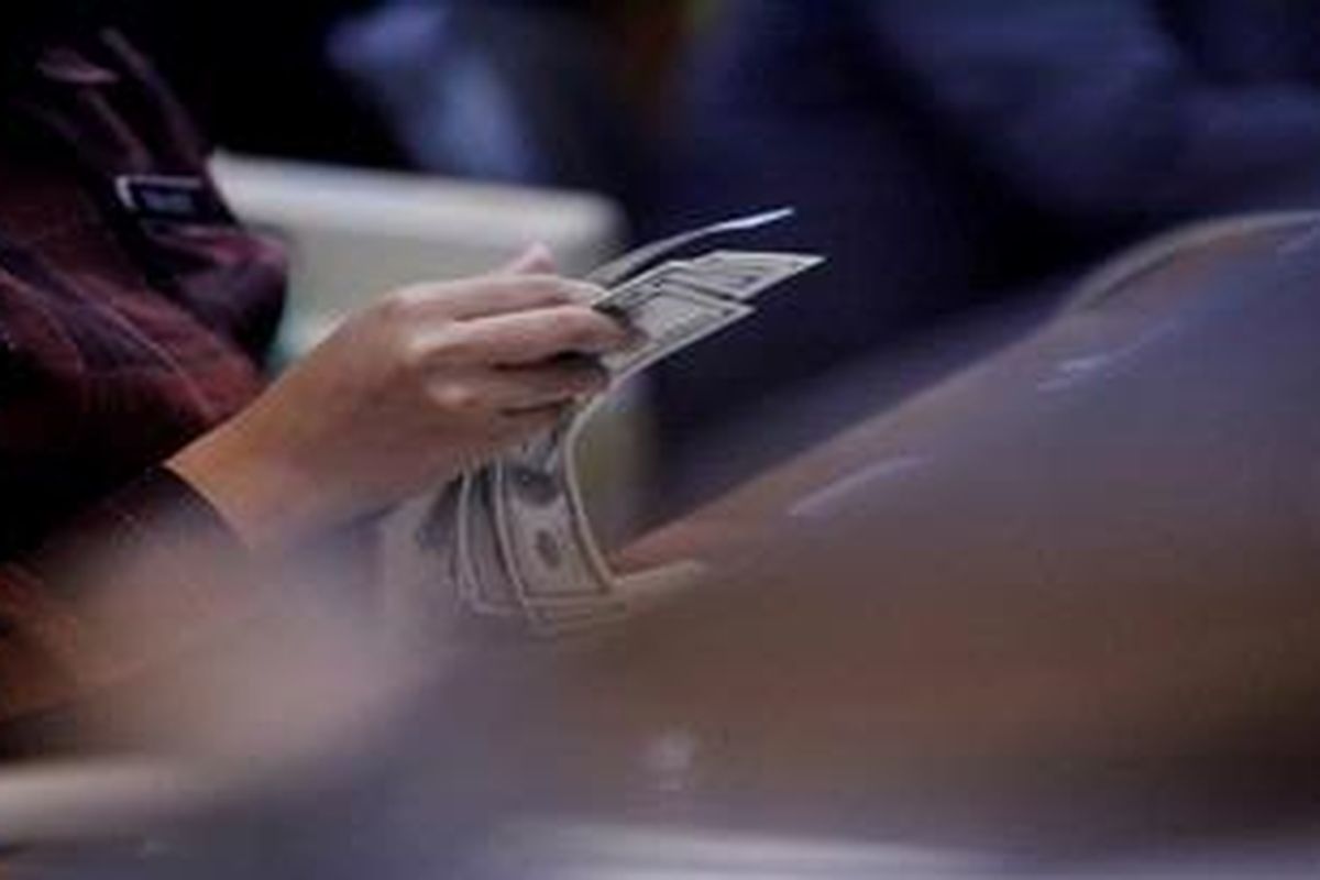 Petugas memeriksa kondisi lembaran Dollar AS yang akan dijual di tempat penukaran valuta asing PT Ayu Masagung di Jakarta, Senin (19/11/2012).
