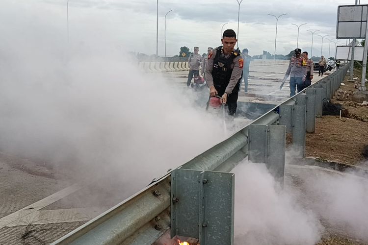 Petugas polisi dari Polres Metro Bekasi Kota saat membersihkan sisa bakaran ban mobil bekas yany dibakar oleh ahli waris dalam aksi penutupan GT Tol Jatikarya, Jatisampurna, Kota Bekasi, Rabu (8/2/2023). Penutupan itu dilakukan karena ahli waris merasa sah atas kepemilikan lahan GT Jatikarya.