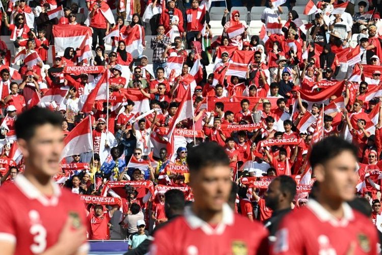 Suporter memberikan dukungan untuk timnas Indonesia dalam laga 16 besar Piala Asia 2023 kontra Australia di Stadion Jassim bin Hamad, Qatar, 28 Januari 2024. Piala Asia 2023 Qatar telah memecahkan rekor penonton terbanyak. (Photo by HECTOR RETAMAL / AFP)