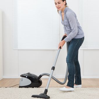 Ilustrasi membersihkan karpet dengan vacuum cleaner. 