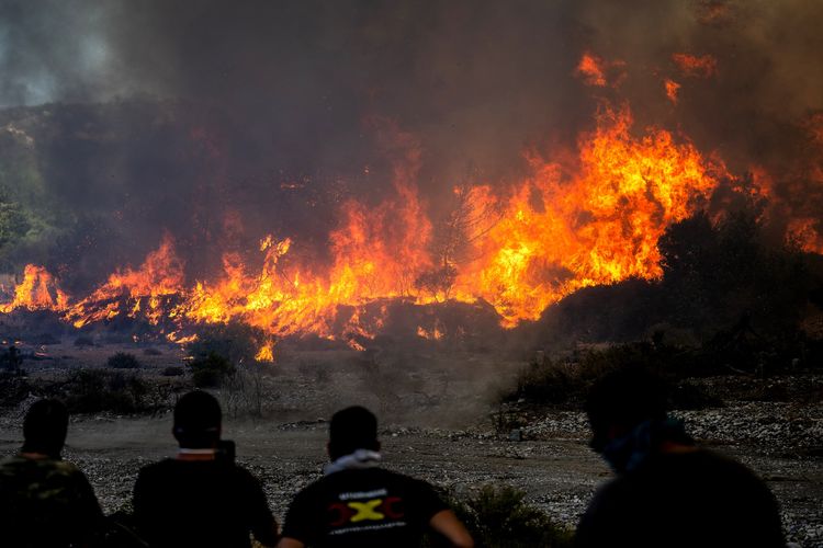 Warga lokal menyaksikan kebakaran hutan di dekat desa Vati, utara kota pesisir Gennadi di selatan Pulau Rhodes, Yunani, Selasa (25/7/2023).