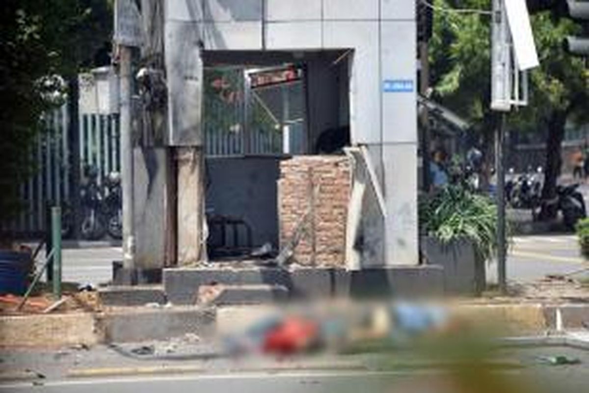 Dua jenazah terlihat di tepi jalan sebelah pos polisi yang rusak setelah ledakan menghantam kawasan Jalan MH Thamrin, Jakarta Pusat, 14 Januari 2016. Serangkaian ledakan menewaskan sejumlah orang, terjadi baku tembak antara polisi dan beberapa orang yang diduga pelaku.