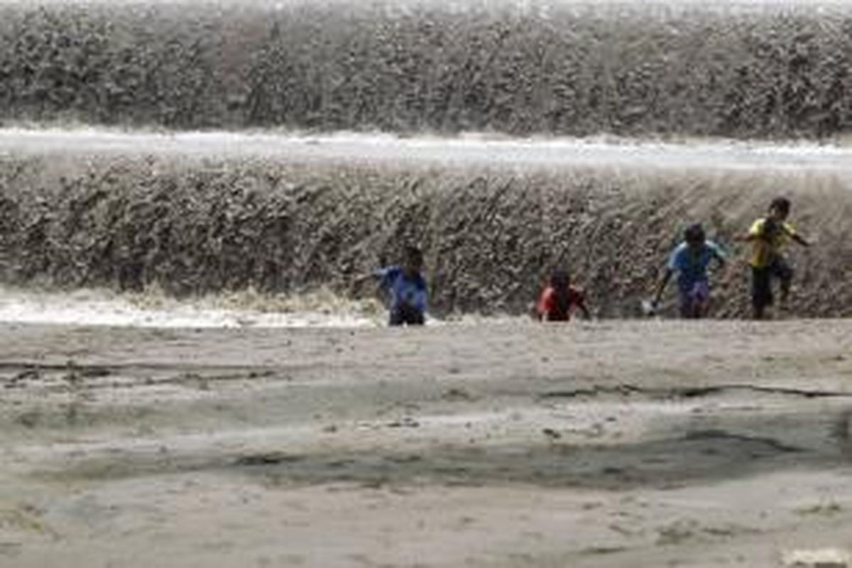 Anak-anak bermain di kebun yang tertimbun lahar hujan dari letusan Gunung Kelud, di sekitar aliran Sungai Konto, Desa Darmawulan, Kediri, Jawa Timur, Rabu (19/3/2014). Banjir lahar merusak pada Selasa (18/2/2014) malam menyebabkan ratusan hektar sawah dan kebun warga, serta bangunan rumah warga. 