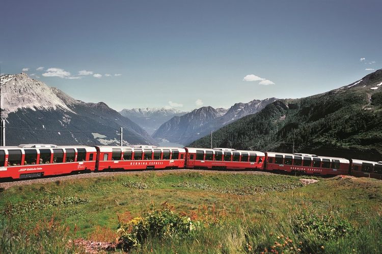 Kereta Bernina Express melintasi rel dekat Stasiun Alps Grum. 