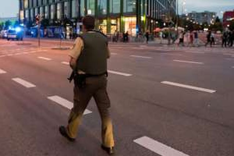 Seorang polisi bersiaga mengamankan proses evakuasi pengunjung pusat perbelanjaan Olympia Einkaufzentrum OEZ di Munich, Jerman, Jumat (22/7/2016), setelah serangan bersenjata di pusat perbelanjaan itu. Sembilan orang dilaporkan tewas.