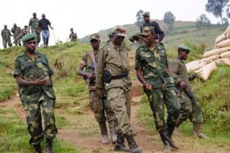 Foto yang diambil pada Juli 2012 ini menampilkan pemimpin pemberontak M23 Kolonel Sultani Makenga (kanan dan loreng hijau) tengah berada di sebuah kawasan perbukitan di dekat perbatasan dengan Uganda. Kini Makenga diyakini berada di bawah perlindungan militer Uganda.