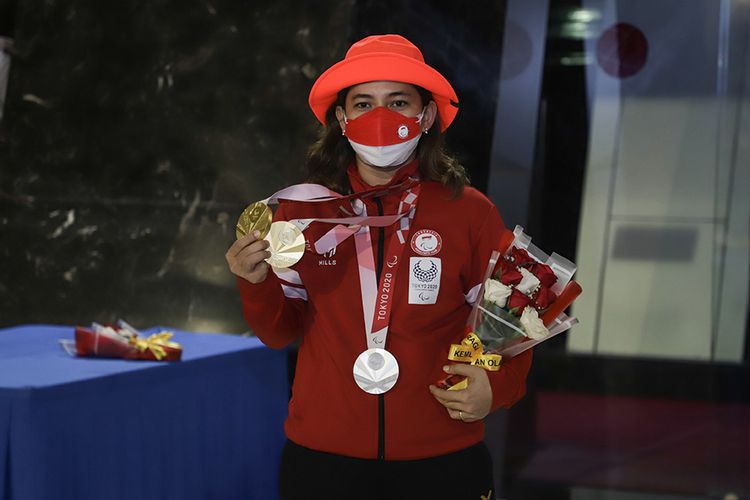 Peraih dua medali emas dan satu medali perak Cabor Para Badminton Leani Ratri Oktila berpose dengan medali emas Paralimpiade Tokyo 2020 setibanya di Bandara Internasional Soekarno Hatta, Tangerang, Banten, Selasa (7/9/2021). Kontingen Indonesia berhasil membawa pulang sembilan medali pada Paralimpiade Tokyo 2020.