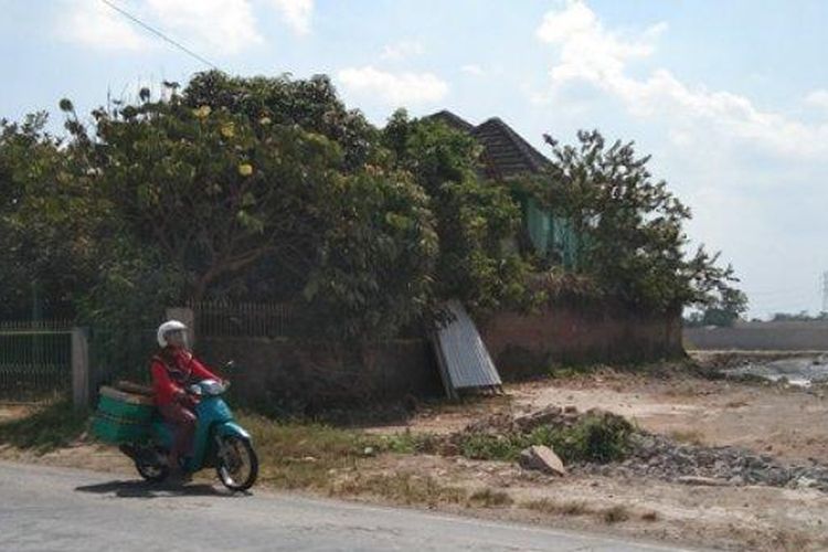 Seorang pengendara sepeda motor melintas di depan rumah yang kokoh berdiri di sekitar proyek Tol Yogyakarta-Solo di Kahuman, Ngawen, Klaten, Kamis (11/8/2022) 
