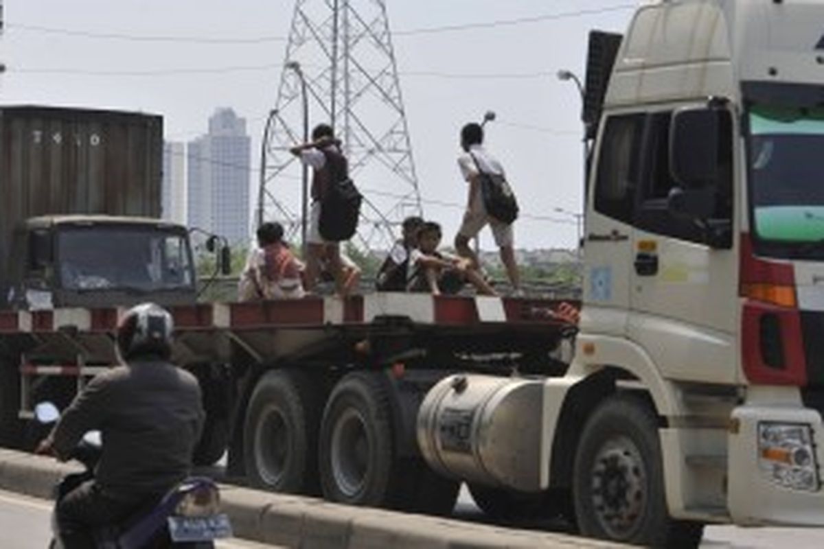 Sejumlah pelajar menumpang truk trailer yang melintasi Jalan RE Martadinata, Jakarta, saat pulang sekolah, Selasa (21/2/2012). KOMPAS/IWAN SETIYAWAN 