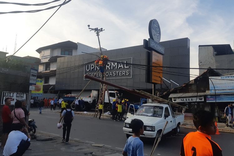 Petugas gabungan berusaha mendirikan tiang listrik yang rubuh di Jalan Raya Kebon Jeruk, Jakarta Barat, Senin (21/10/2019)