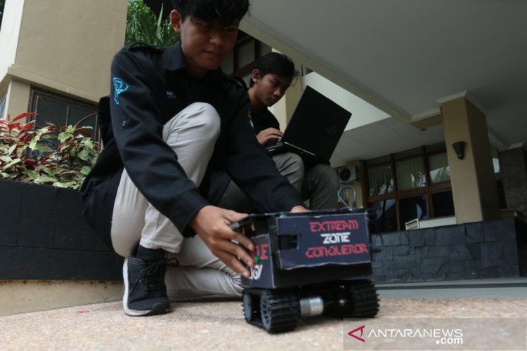 Dua mahasiswa sedang mencoba mengoperasikan robot penemu korban bencana alam 