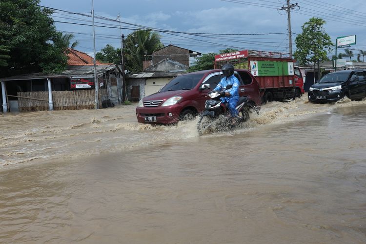 Banjir akibat jebolnya tanggul 2 sungai menggenangi jalan raya Jombang - Madiun, di Desa Gondangmanis, Kecamatan Bandar Kedungmulyo, Kabupaten Jombang, Jawa Timur, Kamis (4/2/2021).