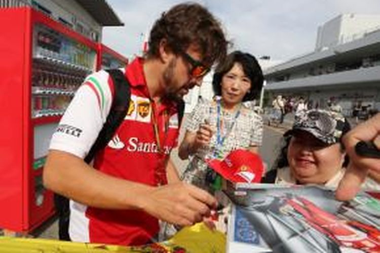 Pebalap Scuderia Ferrari asal Spanyol, Fernando Alonso, memberikan tanda tangan kepada para penggemar saat tiba di Sirkuit Suzuka, Jepang, Sabtu (4/10/2014).
