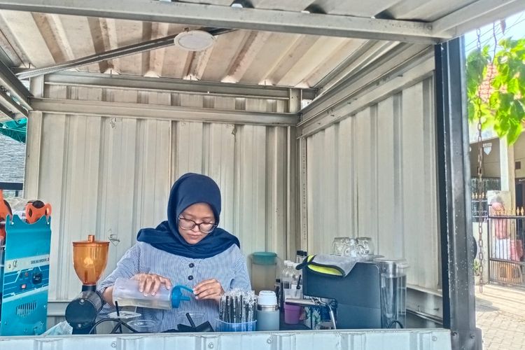 Pramita Putri, penjual es kopi saat melayani pelanggan di warungnya, Jalan Tropodo Indah, Waru, Sidoarjo, Selasa (8/10/2024).