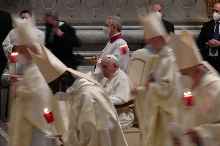 Para Kardinal dan Uskup berjalan dalam prosesi melewati Paus Fransiskus selama misa Malam Paskah pada Sabtu (16/4/2022), di Basilika Santo Petrus di Vatikan. 