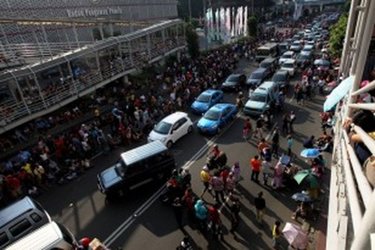 Warga menunggu arak-arakan Jakarnaval 2013 di Jalan MH Thamrin, Jakarta, Minggu (30/6/2013). Jakarnaval 2013 yang diikuti sekitar 4500 peserta tersebut sebagai rangkaian peringatan HUT Ke-486 DKI Jakarta.