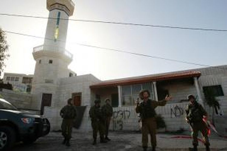 Tentara Israel, Rabu (26/2/2015), berjaga di depan sebuah masjid yang diduga kuat dibakar di desa Jaba dekat kota Bethlehem, Tepi Barat.
