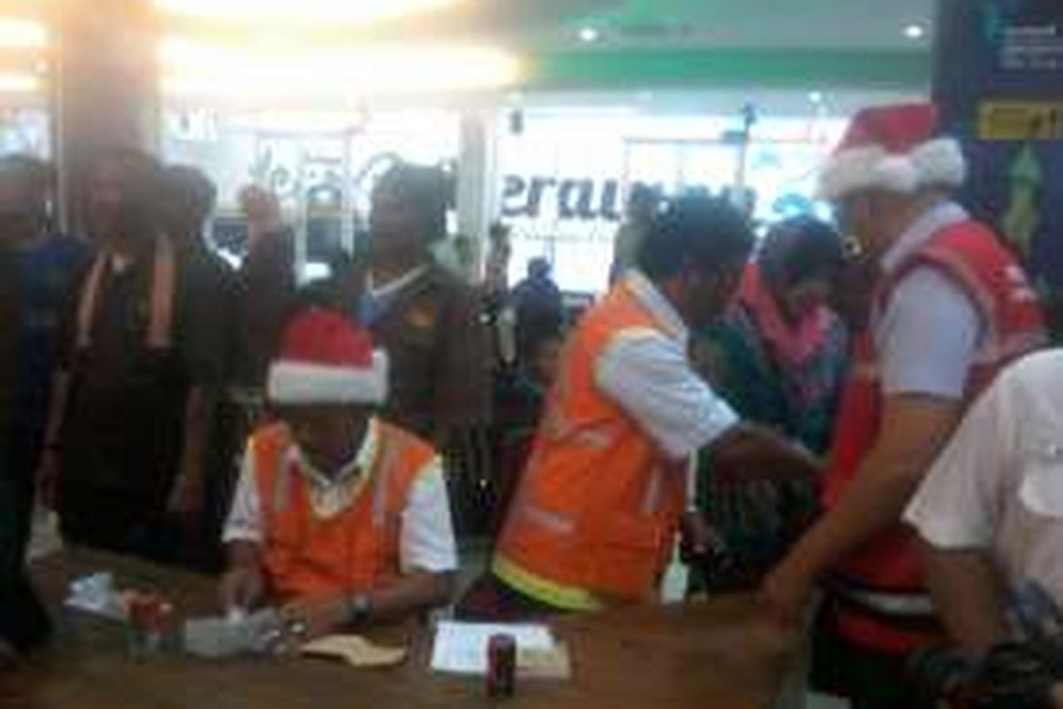 Petugas Pelabuhan Internasional Soekarno Hatta mengenakan topi sinterklas saat memeriksa tiket dan barang bawaan calon penumpang, Senin (19/12/2016).