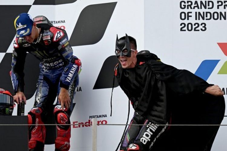 Pebalap Aprilia, Maverick Vinales (kanan), berkostum Batman saat naik ke podium MotoGP Mandalika 2023. Pada balapan utama yang digelar Minggu (15/10/2023) siang WIB di Mandalika International Circuit, Lombok Tengah, Nusa Tenggara Barat, Vinales berhasil finis kedua di belakang sang pemenang Francesco Bagnaia dari tim Ducati. (Foto oleh SONNY TUMBELAKA/AFP)