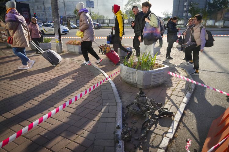 Orang-orang melewati sisa-sisa drone setelah serangan pagi di Kyiv, Ukraina, Senin, 17 Oktober 2022.