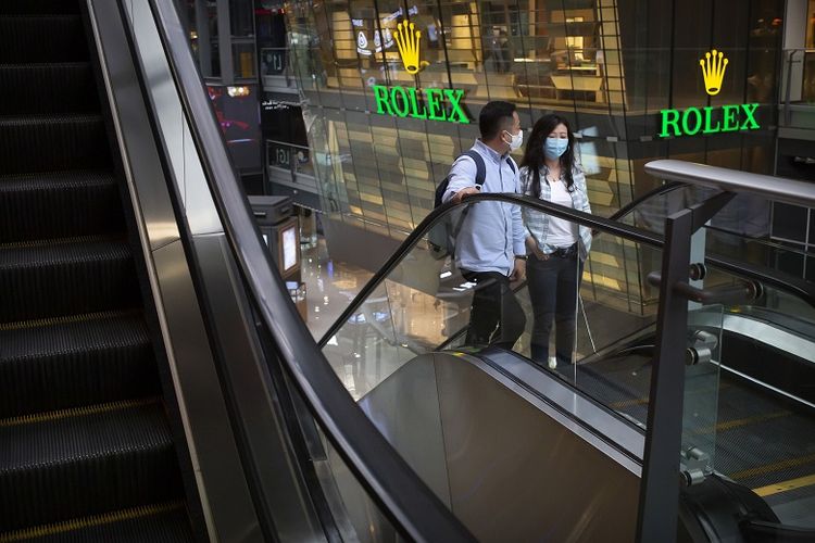 Orang memakai masker untuk melindungi diri dari virus corona sedang menaiki eskalator di sebuah pusat perbelanjaan di Beijing, China pada (15/5/2020). 