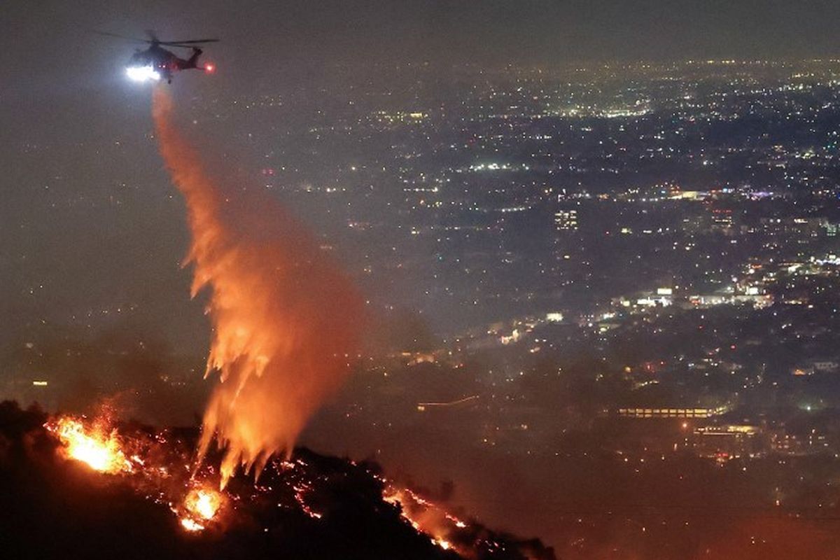 Helikopter menyemprotkan air untuk memadamkan kebakaran hutan Los Angeles atau Sunset Fire di Hollywood Hills, Negara Bagian California, Amerika Serikat, Rabu (8/1/2025).