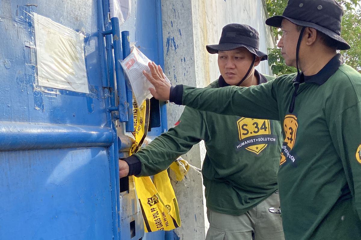 Petugas saat mencoba membuka pintu gudang UD Sentoso Seal yang tergembok berlapis, Kamis (15/5/2025)