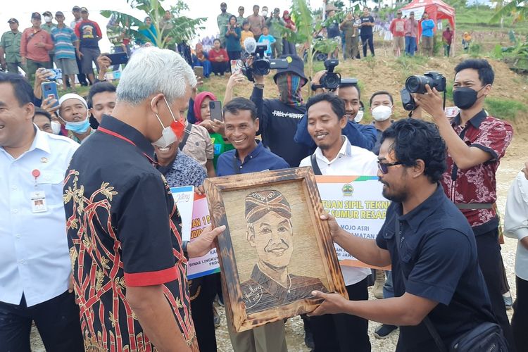 Ganjar Pranowo menerima gambar berupa wajahnya yang dibuat dari pelepah pisang saat berkunjung ke Puncak Serut, Kecamatan Jiken, Kabupaten Blora, Jawa Tengah, Rabu (26/10/2022)