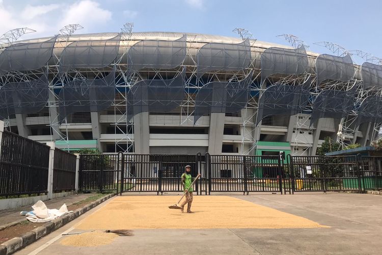 Seorang warga tengah menjemur padi di pintu gerbang Stadion Gelora Bandung Lautan Api (GBLA).