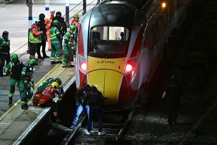 Petugas polisi dan anggota layanan darurat menyisir rel di bawah kereta LNER Azuma di Stasiun Huntingdon di Huntingdon, Inggris timur, pada 1 November 2025, menyusul penusukan massal di dalam kereta. Kepolisian Inggris mengatakan mereka telah menangkap dua tersangka pada Sabtu ketika sejumlah orang dibawa ke rumah sakit setelah penusukan di dalam kereta di Cambridgeshire, Inggris timur.