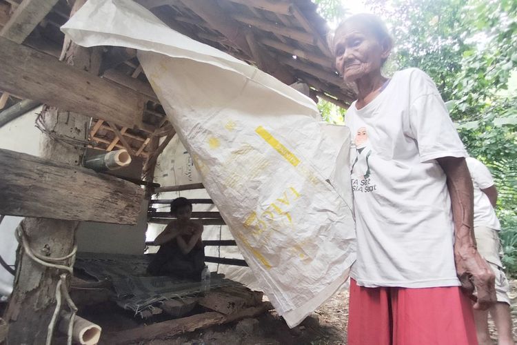 Nenek Desti (81) melihat kondisi anaknya Karto (43) yang mengalami gangguan jiwa hingga terpaksa tinggal di tempat bekas kandang sapi setelah rumahnya ambruk di Dusun Pangebonan RT 03, RW 06, Desa Bandungsari, Banjarharjo, Brebes, Jateng, Jumat (19/1/2024).
