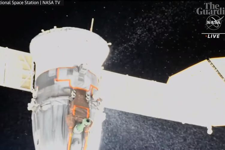 Tangkapan layar dari NASA TV yang menampilkan partikel-partikel putih yang berpendar keluar dari kapsul Soyuz yang mengalami kebocoran cairan pendingin.