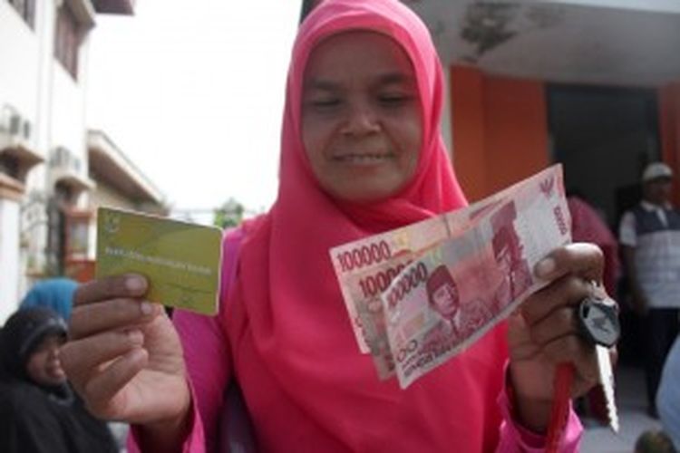 Seorang warga menunjukkan dana Bantuan Langsung Sementara Masyarakat (BLSM) yang diterimanya di Kantor Pos Pembantu, Lambaro, Kecamatan Ingin Jaya, Aceh Besar, Kamis (27/6/2013).   