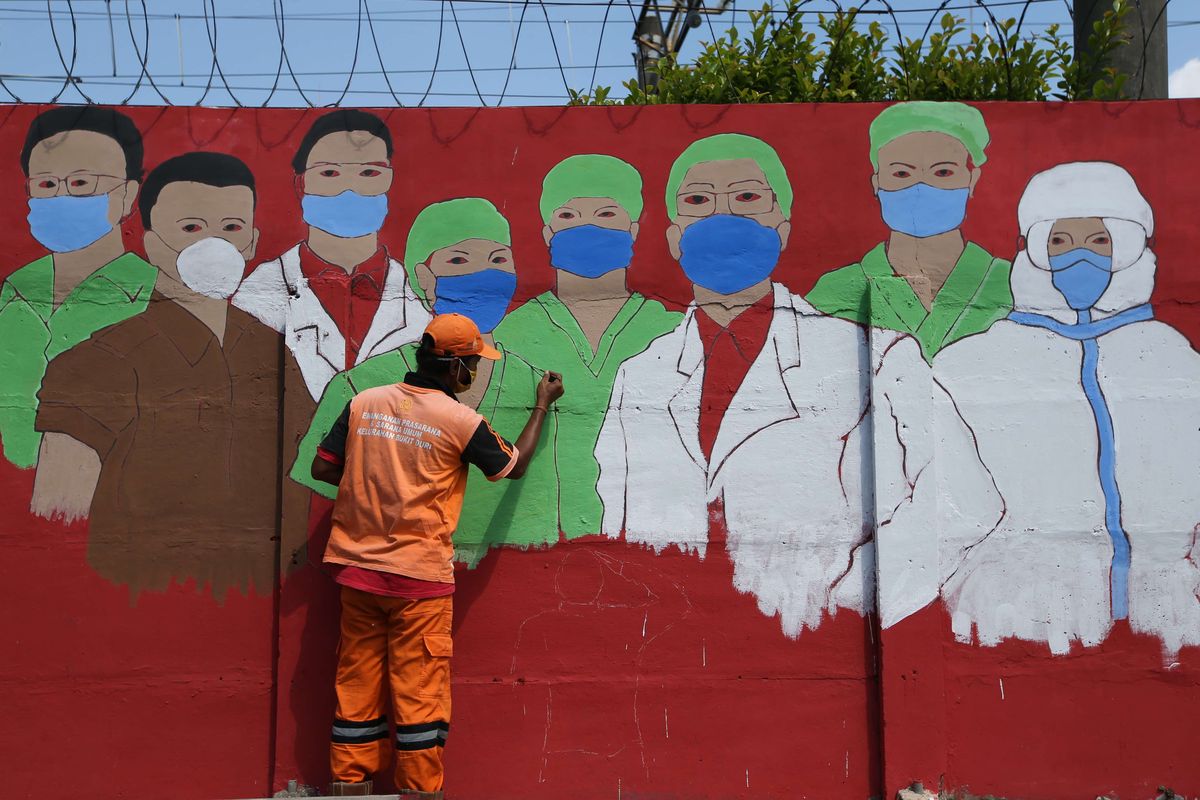 Bonay, one of the Public Facility Maintenance Agency city cleaners in Jakarta, paints a mural showing medical personnel wearing masks amid the increasing number of Covid-19 cases in the Indonesian capital on August 27, 2020. 