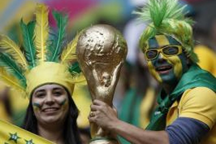 Suporter tim nasional Brasil membawa replika trofi Piala Dunia saat menyaksikan pertandingan Grup A antara timnya dan Kamerun, di Estadio Nacional, Brasilia, 23 Juni 2014.