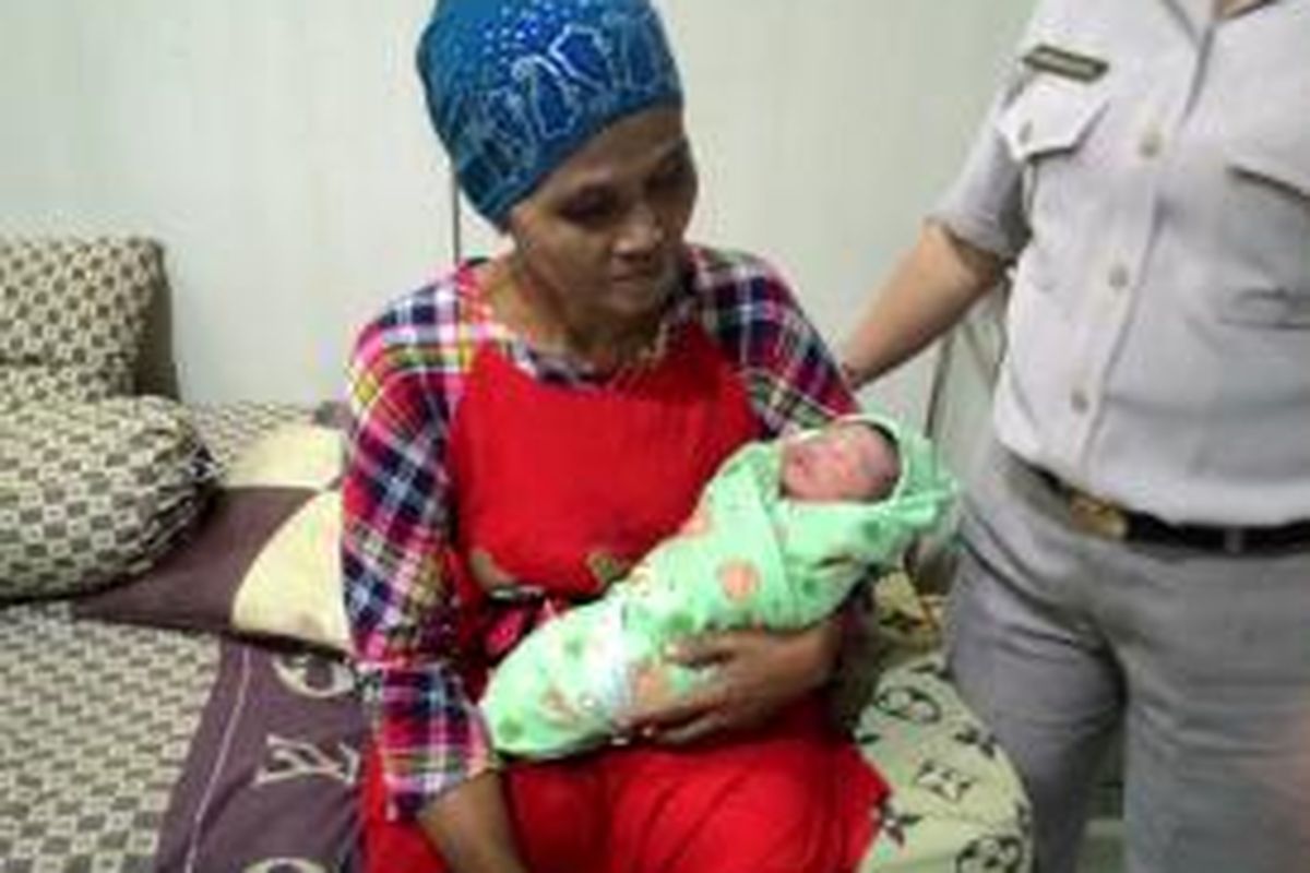 Maimunah menggendong cucu perempuannya, yang lahir di Polda Metro Jaya, Rabu (1/7/2015). 