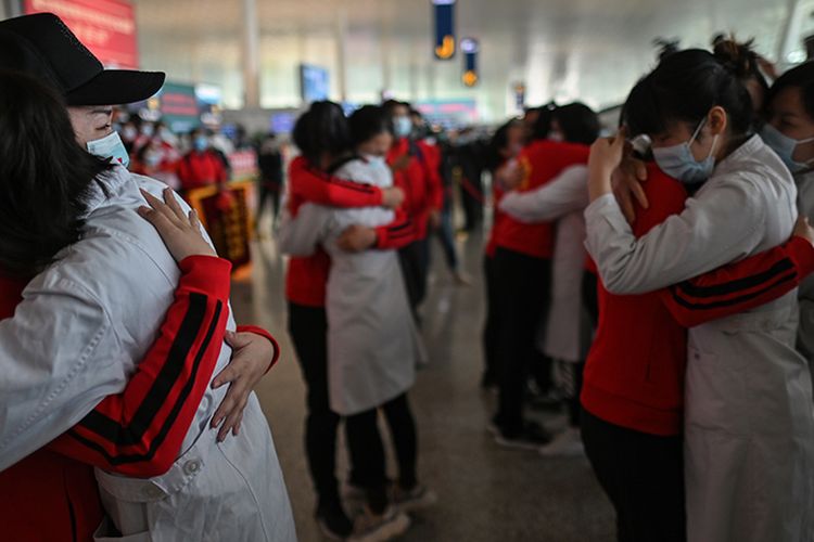 Para petugas medis dari Provinsi Jilin menangis memeluk rekan yang bersama-sama selama menangani pasien corona, dalam sebuah acara perpisahan di Bandara Tianhe yang baru dibuka kembali di Wuhan, Hubei, China, Rabu (8/4/2020). Ribuan orang bergegas meninggalkan Wuhan setelah otoritas mencabut kebijakan lockdown selama lebih dari dua bulan di lokasi yang diketahui sebagai episenter awal virus corona tersebut.