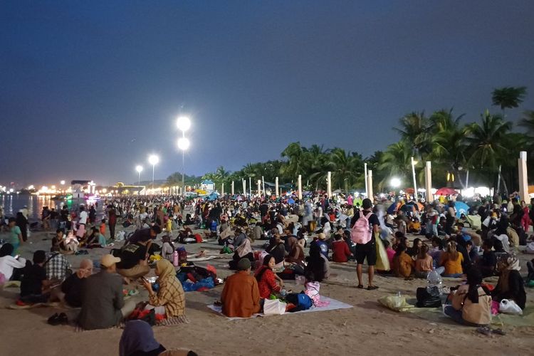 Potret wisatawan yang memadati Pantai Lagoon, Taman Impian Jaya Ancol, Minggu (31/12/2023) malam.