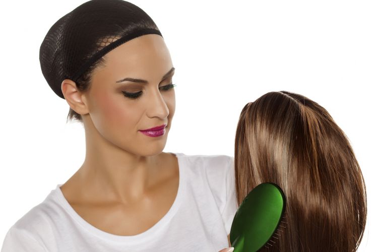 young woman with a wig cap combing her wig