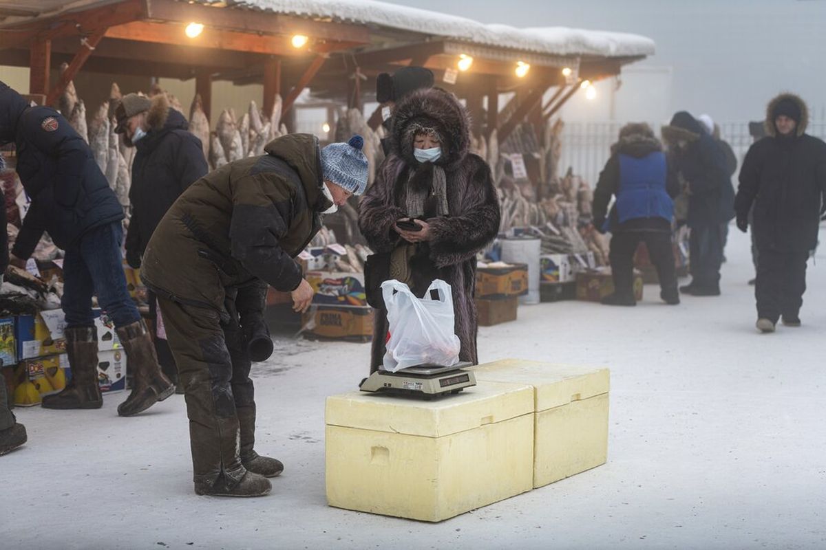 Orang-orang dengan pakaian tebal membeli ikan beku di pasar saat suhu turun menjadi sekitar minus 50 derajat Celsius di Yakutsk, Rusia, Sabtu, 16 Januari 2021.