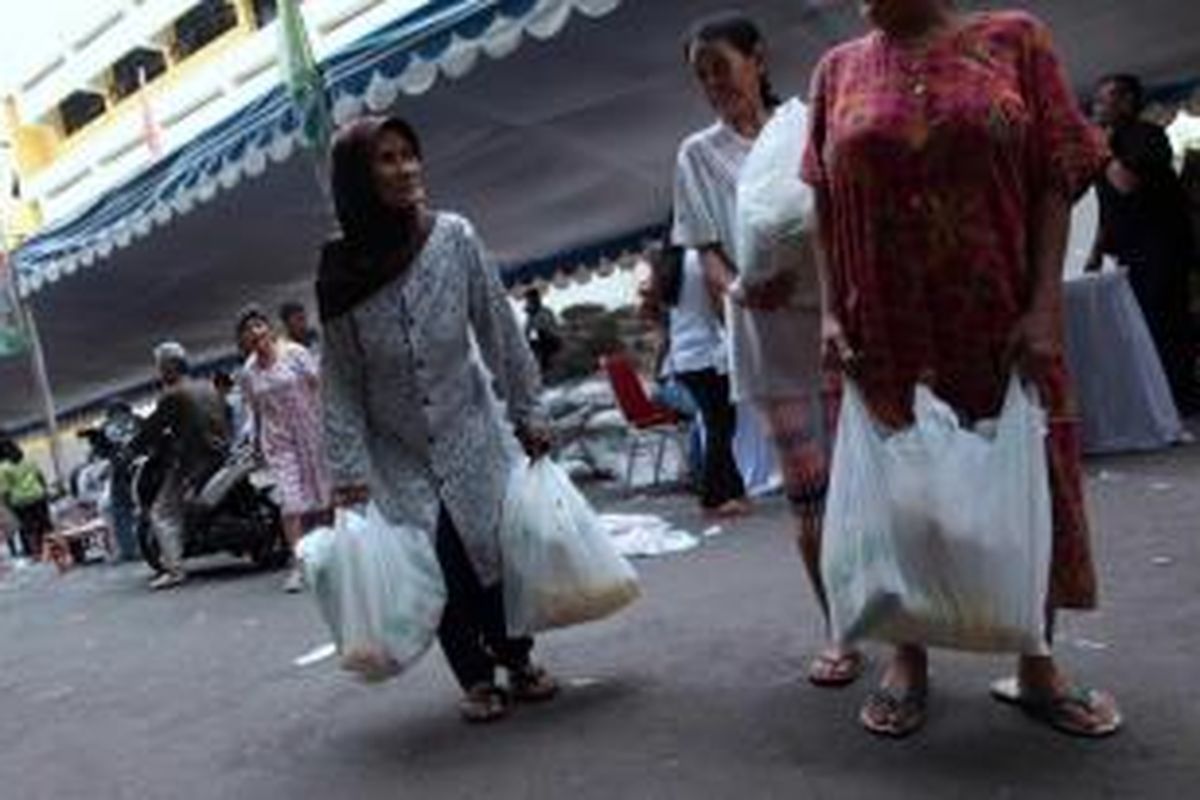 Warga membawa paket sembako yang dibeli di  pasar murah yang digelar oleh PT Jamsostek di halaman kantor Sudin Pekerjaan Umum di Kawasan Jatinegara, Jakarta Timur, Jumat (27/6/2013). Pasar murah itu untuk meringankan beban warga menjelang Ramadhan.